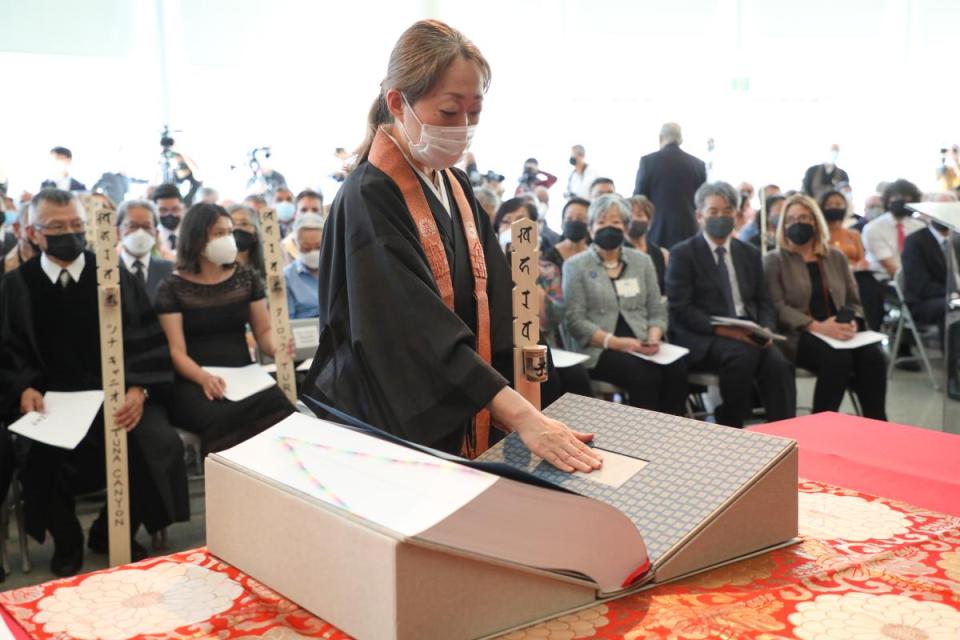 Woman touches ceramic piece made of soil from all of the camps in the Ireichō